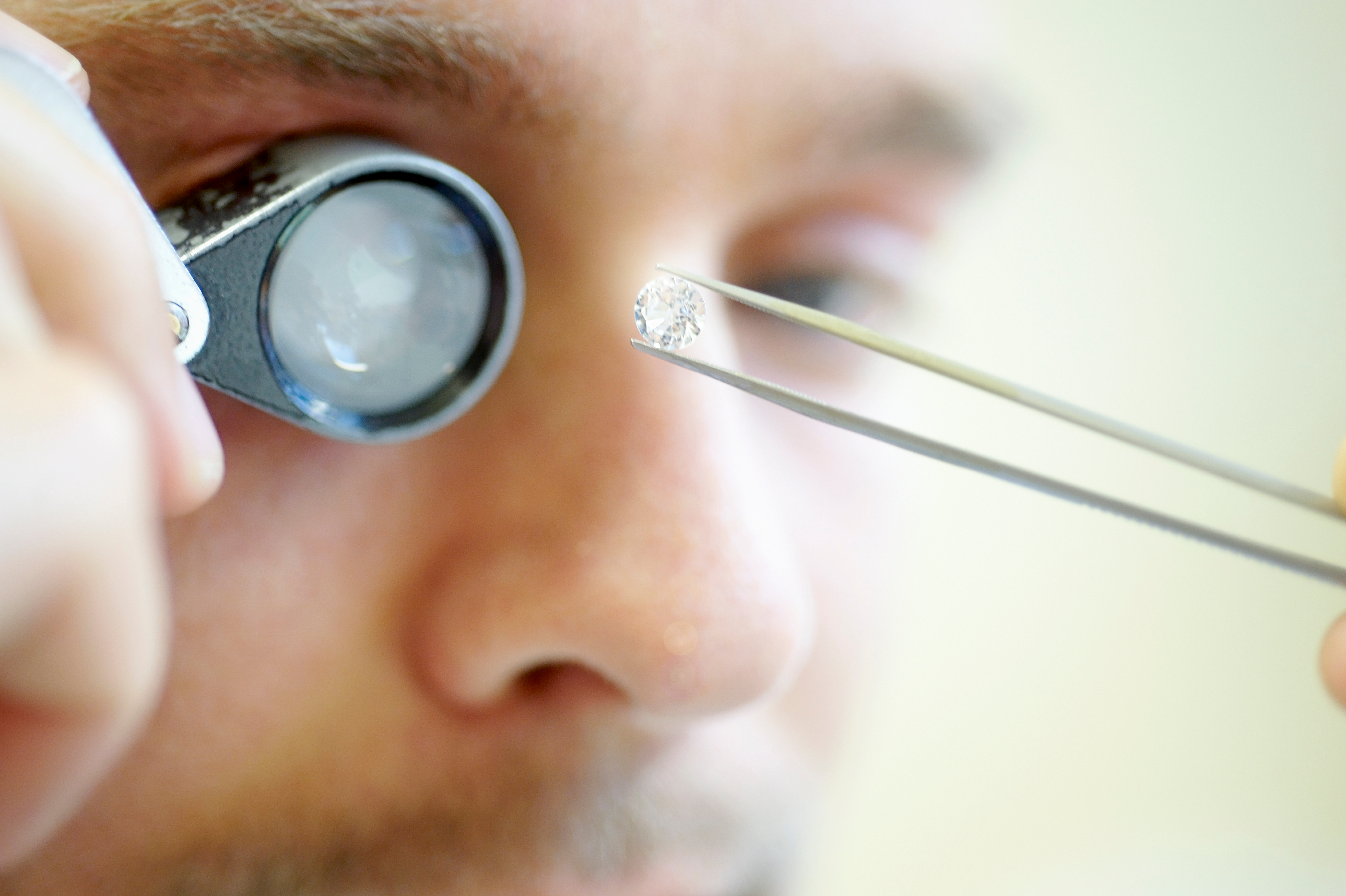 Jeweler examining diamond with magnifying loupe